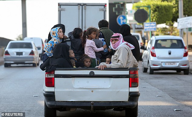 More than a dozen people, many of them young children, cram into the back of a pickup truck as they seek refuge in the capital Beirut