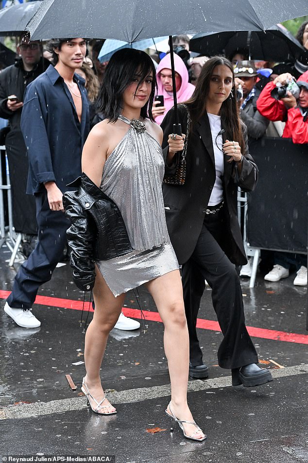 The 27-year-old 'hyperpop' star - who recently outshone rival Sabrina Carpenter - braved France's 16 degree Celsius thunderstorms as she arrived at the Palais de Tokyo with an umbrella holder