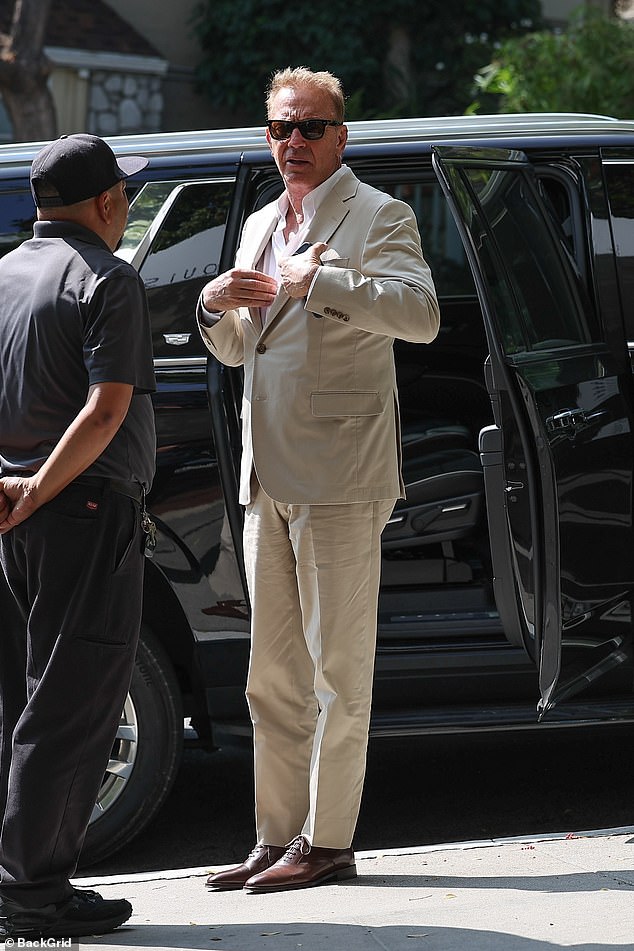 Costner stepped out of his car at the hotel wearing a white shirt slightly open beneath a beige suit jacket.