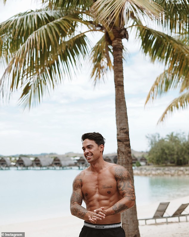 John was also photographed in a very relaxed pose on a wooden beach chair before removing his shirt and showing off his sculpted torso as he stood in front of a palm tree