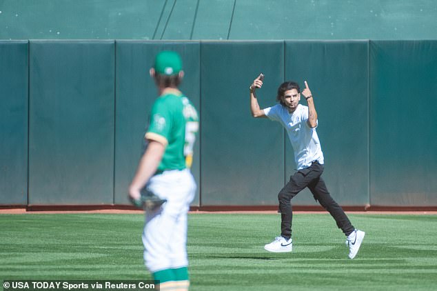 A fan runs onto the field during the ninth inning of the final track and field meet in Oakland