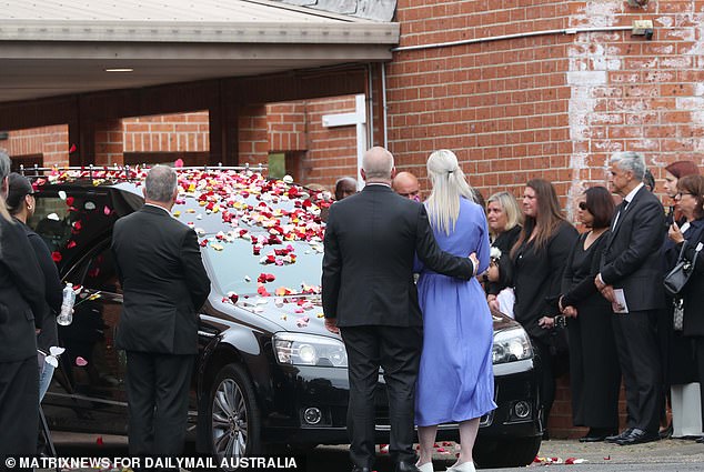 Mourners covered the hearse with flower petals before it left for the cemetery after the funeral service