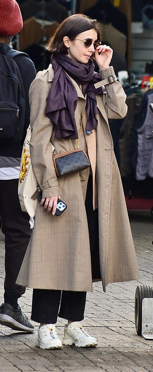 The actress ditched her character's bright and quirky fashion sense and opted for a more subdued look as she wrapped up in the brown trench coat.