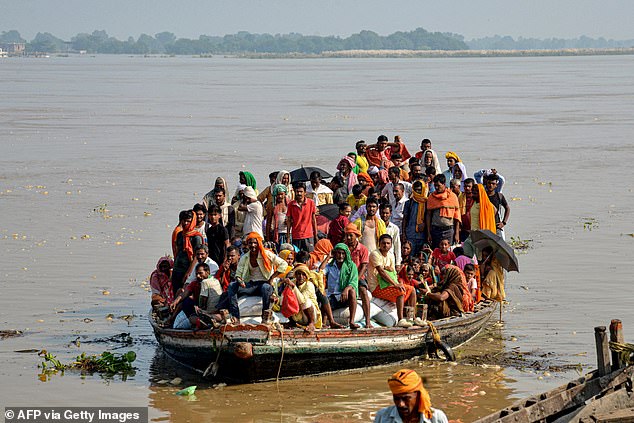 Flood-affected people along with their belongings move to a safer place in a boat after the water level of river Ganga rose following heavy rains in Patna on September 23