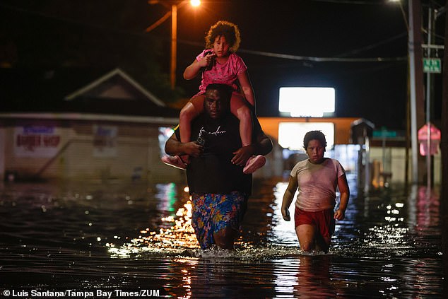 A family wades through floodwaters in Crystal River, Florida, in the early hours of Friday