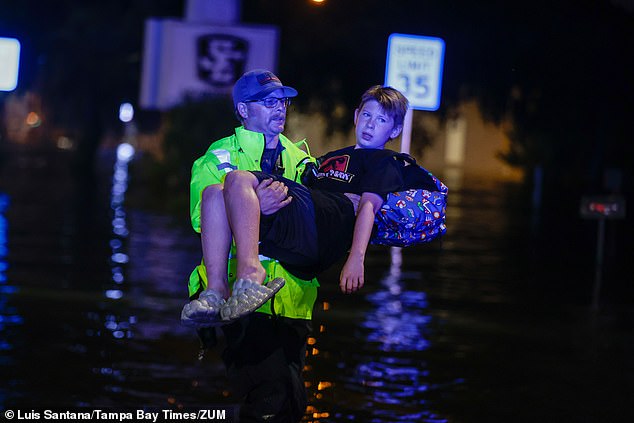 A Citrus County firefighter carries 11-year-old Michael Cribbins through the water Friday morning in Crystal River, Florida