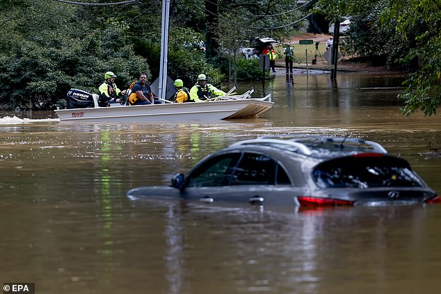 Members of the Atlanta Fire Rescue Department's Swift Water Rescue Team move Darryl Hall to dry land after his home was inundated by flooding in Atlanta, Georgia