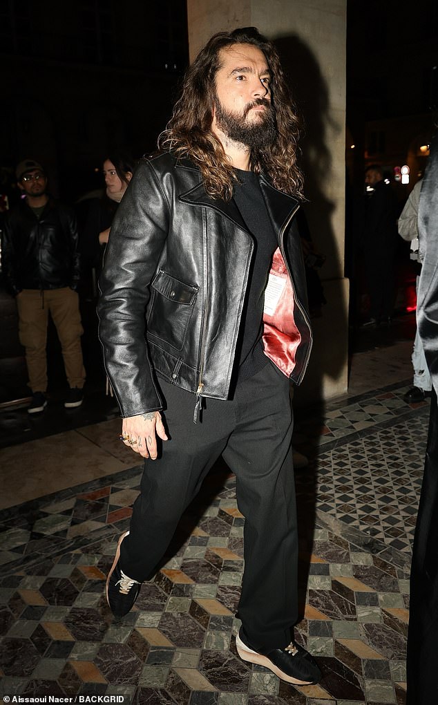 Tom wore a stylish black leather jacket and wide trousers, paired with trainers and a simple T-shirt