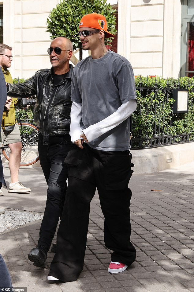 Romeo wore a white long-sleeved top and an oversized gray T-shirt, which he paired with baggy black cargo pants and a pair of red Puma sneakers.