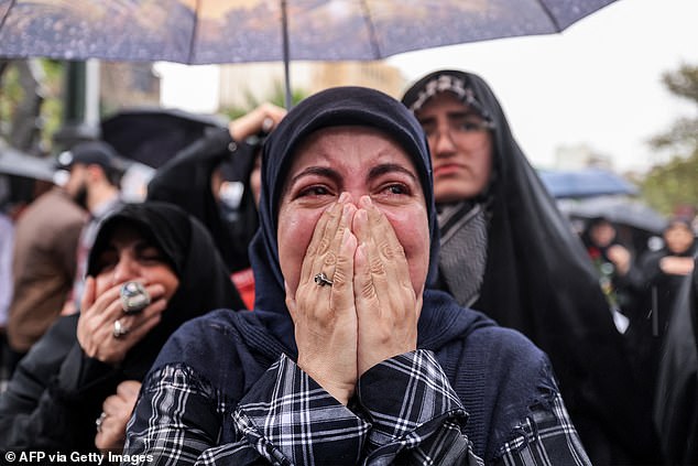 A woman reacts as she stands in the rain with other protesters during an anti-Israel protest in Tehran's Palestine Square on September 28, 2024, after the Iran-backed Lebanese Hezbollah group confirmed reports of the assassination of its leader Hassan Nasrallah in Israeli air strike in Beirut the previous day