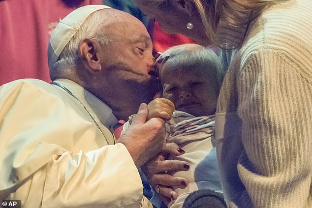 Pope Francis kisses a child yesterday during the Hope Happening youth festival at Brussels Expo, Belgium