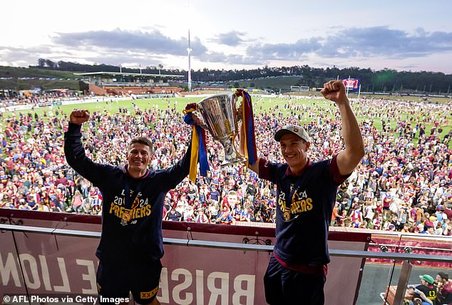 Dayne Zorko (left) and Hugh McCluggage celebrate with the undamaged 2024 trophy in front of supporters at home in Brisbane late on Sunday