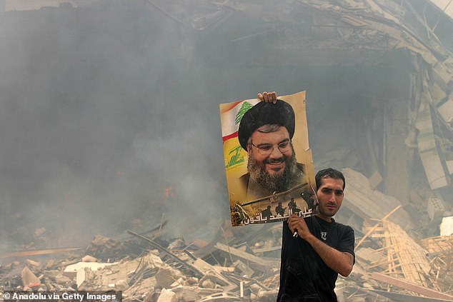 A Lebanese man shows a poster of Hezbollah leader Hassan Nasrallah that he found among the rubble of his home in July 2006