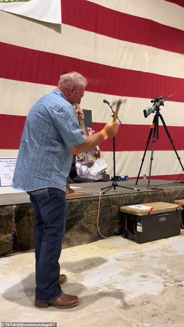 The video of the moment shows the man going on stage to collect the prize, but immediately starts smashing the guitar with a hammer handed to him by the auctioneer