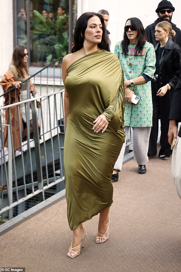 Ashley Graham turned heads in an olive green maxi dress as she made a very stylish entrance to the Atlein runway show during Paris Fashion Week on Sunday