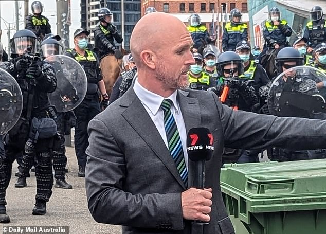 Guns up: Channel 7 fanatic Paul Dowsley was lucky not to be shot himself. Behind him, several police officers could be seen in the background taking aim at him.