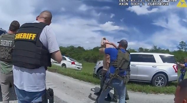 Routh, 58, is seen struggling with officers with his shirt and arms over his head after being surrounded by police on a road outside West Palm Beach, Florida