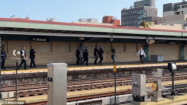 The horrific incident took place near the 4th Avenue 9th Street station. (pictured: officers carrying a covered stretcher onto the platform)