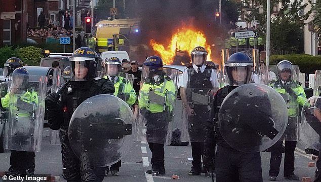 Riot police hold back protesters in Southport on July 30, 2024