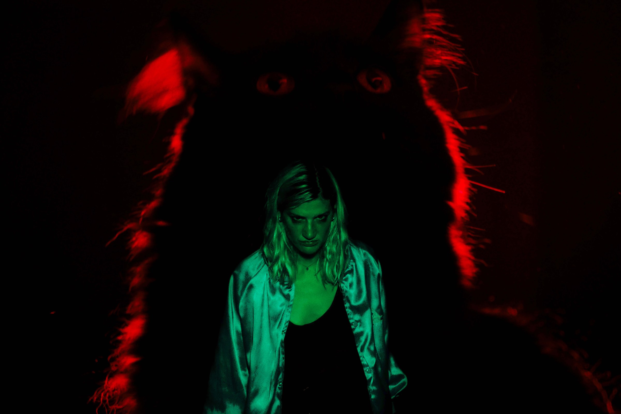 A woman stands in the silhouette of a cat, illuminated by red and green light in Booger.