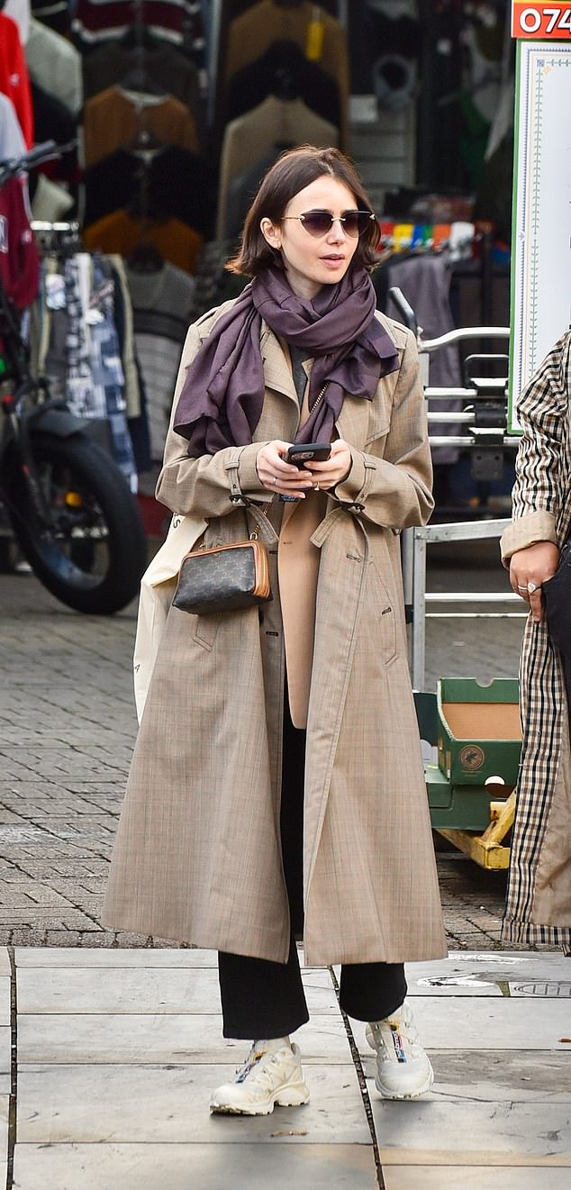 Emily in... Shepherd's Bush Market! Without make-up, Lily Collins looked effortlessly chic in a trench coat and sunglasses as she enjoyed a stroll around London on Wednesday