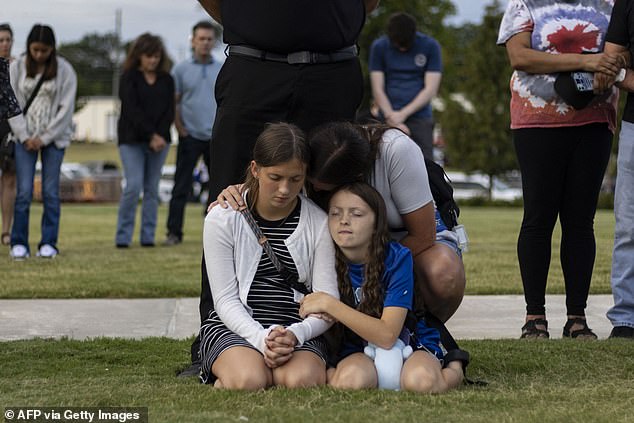 The Winder, Georgia massacre left four people dead and nearly a dozen others injured. Pictured: A mother and her children bow their heads in prayer during a vigil for the victims