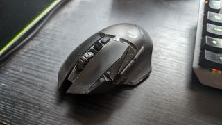 A heavily used Logitech G502 Lightspeed Wireless gaming mouse on a desk.