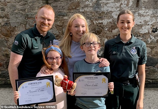 Oliver and Arianna Liddle pose with paramedics John McCook and Monica Hurley after they were honoured for saving their mother Donna's life when she collapsed at home and went into cardiac arrest