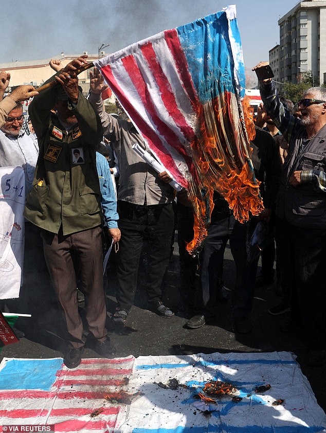 Protesters burn an image of the American flag today during a demonstration against Israel's attacks on Gaza and Lebanon in Tehran, Iran