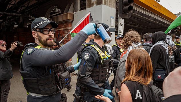 The terror threat has been raised to 'likely' in Victoria as hundreds of protesters are expected to gather at a major defence exhibition (pictured officers at a protest)