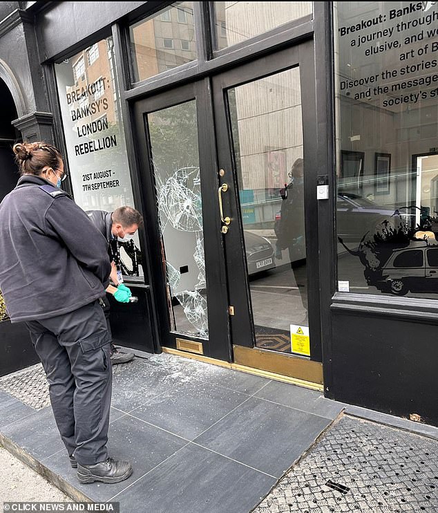 Officers inspect the damaged door outside the Grove Gallery in Fitzrovia, London