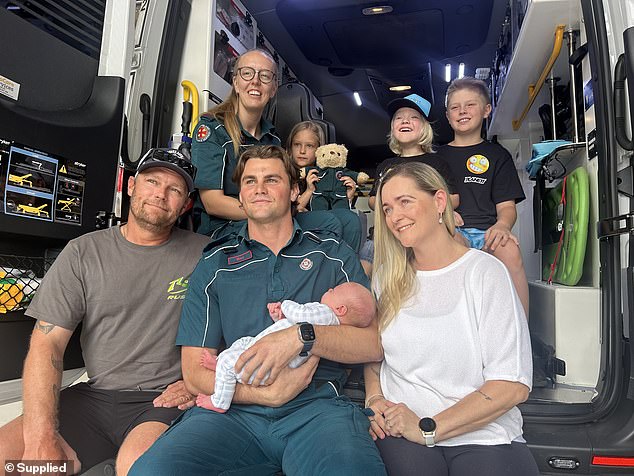 Mother Natalie Beecham (right) almost lost her baby Cruz during a horrific home birth. She is pictured with her husband Troy (far left), children and the paramedics who helped save her life