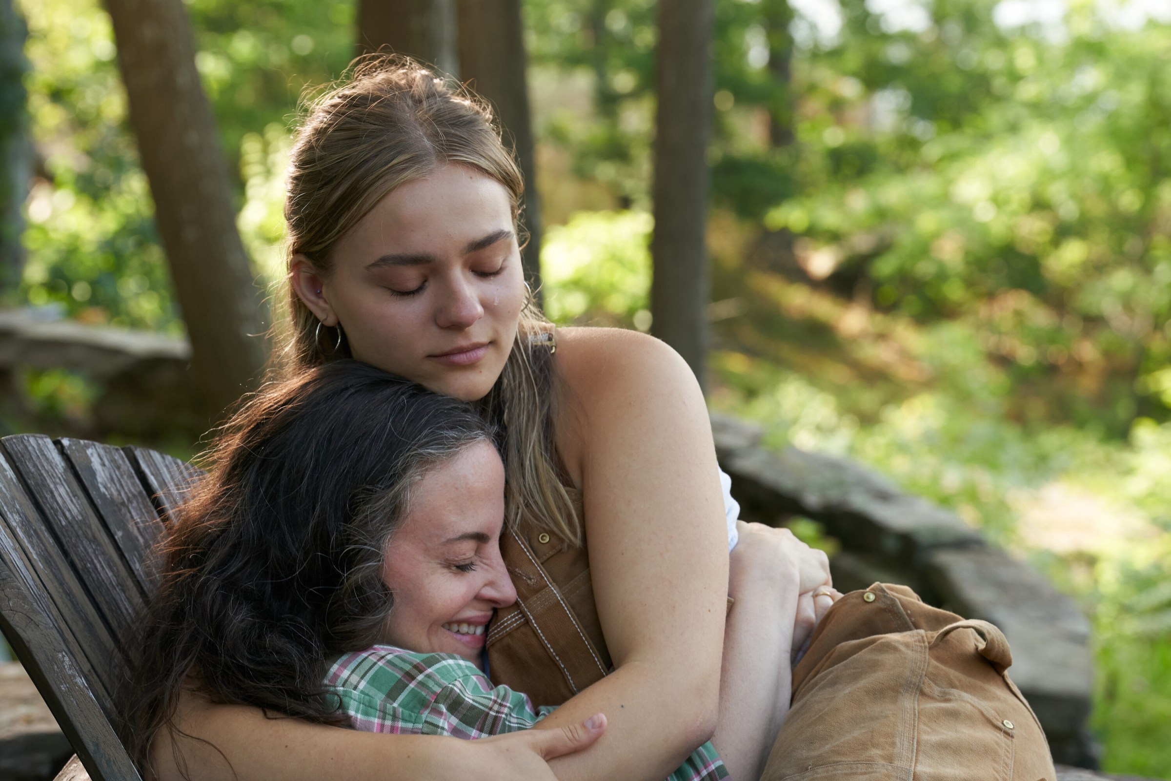 Elliott, a young blonde woman played by Maisy Stella, hugs her mother, played by Maria Dizzia, on a chair outside in My Old Ass