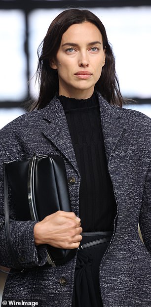 Irina wore an oversized, thick gray wool coat and carried a black leather bag down the runway.