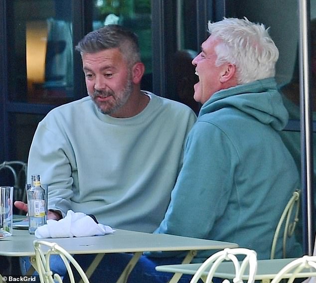 Phillip Schofield appeared to be in high spirits as he smiled during a lunch in London on Thursday with his daughter Molly and male friend Scott Brown, while still wearing his wedding ring