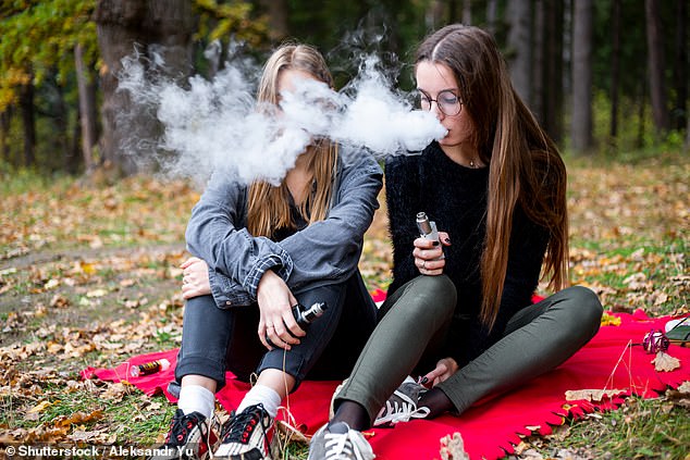 Two teens vaping. Young vapers perform worse in exercise than their peers who don't use e-cigarettes and achieve performance comparable to smokers of the same age, according to a study (stock image)