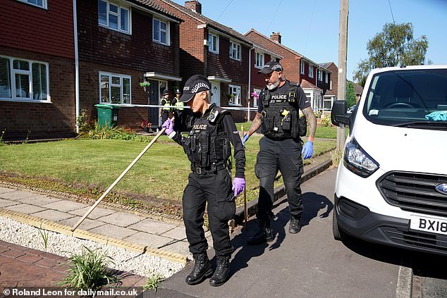 Police officers use batons to search for evidence outside Lovett Avenue home