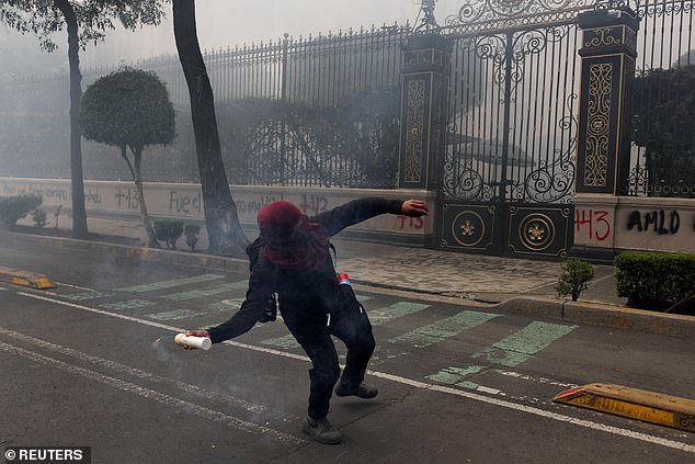 A protester throws a homemade explosive device at the headquarters of the Ministry of the Interior in Mexico City on Monday, following a demonstration against the 43 students of the Rural Normal School in Ayotzinapa, who disappeared on September 26, 2014.