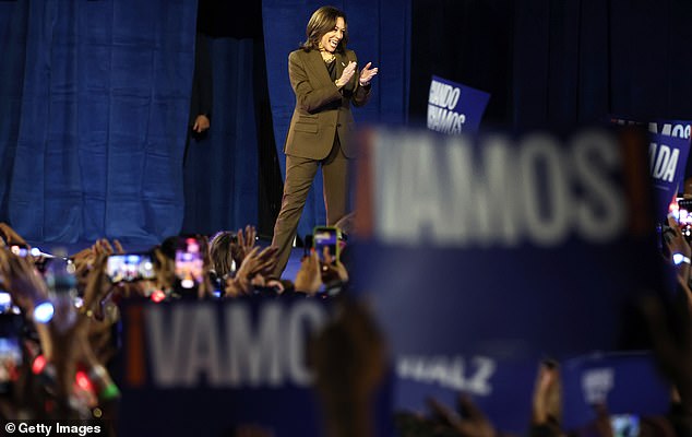 Democratic presidential candidate Vice President Kamala Harris walks on stage carrying campaign signs that read 