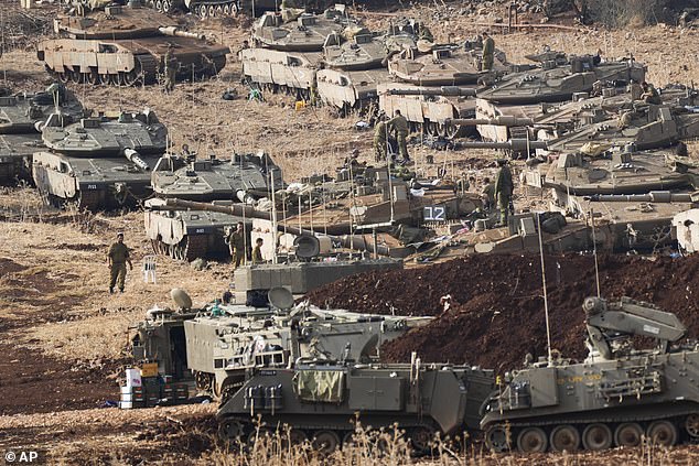 Israeli soldiers work on tanks at a staging area in northern Israel, near the Israel-Lebanon border, October 1, 2024