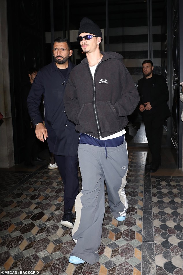 Romeo Beckham wore gray and white striped track pants over navy blue shorts for the outing