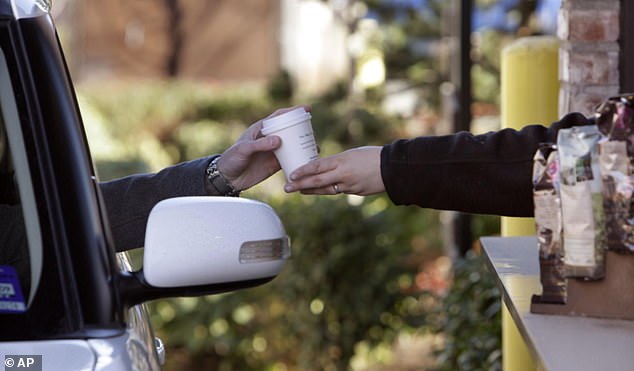 A barista handed a customer a cup of coffee through a drive-thru (stock image)