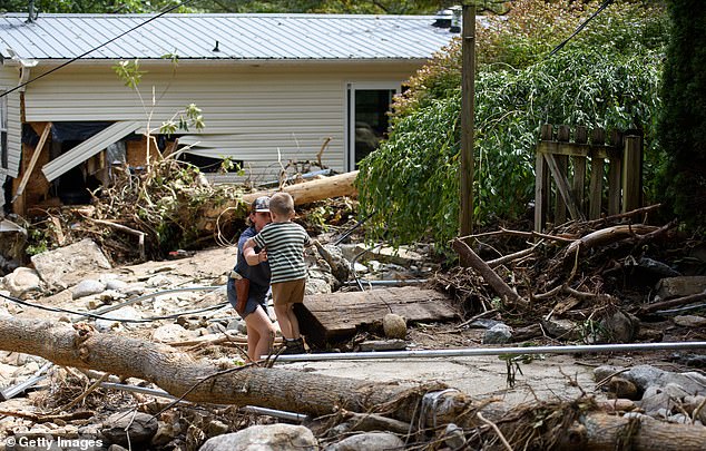 Leo Grindstaff, 12, left, helps his brother Gabe, 4, as he walks to their grandparents' house to rescue items in the aftermath of Hurricane Helene