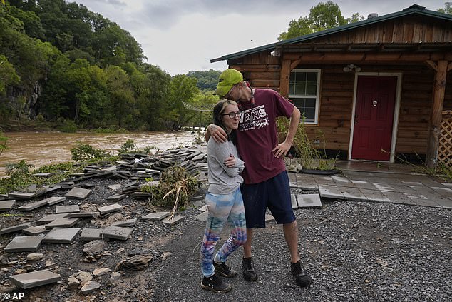 Jonah Wark, right, kisses his wife Sara Martin outside their flood-damaged home on the Pigeon River in the aftermath of Hurricane Helene, September 28, 2024, in Newport, Tennessee