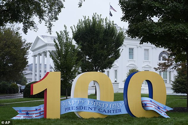 On the north lawn of the White House stands a sign wishing former President Jimmy Carter a happy 100th birthday