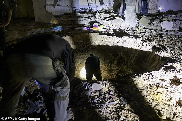 Israeli police inspect a crater left by an exploded projectile in a badly damaged school building in Israel's southern city of Gedera