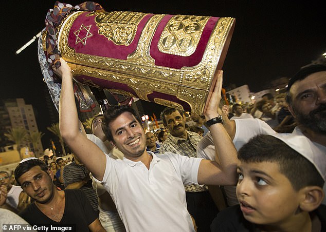 A Jewish man holds a Torah scroll during the Simhat Torah celebration in the Mediterranean coastal city of Netanya, north of Tel Aviv, on September 26, 2013