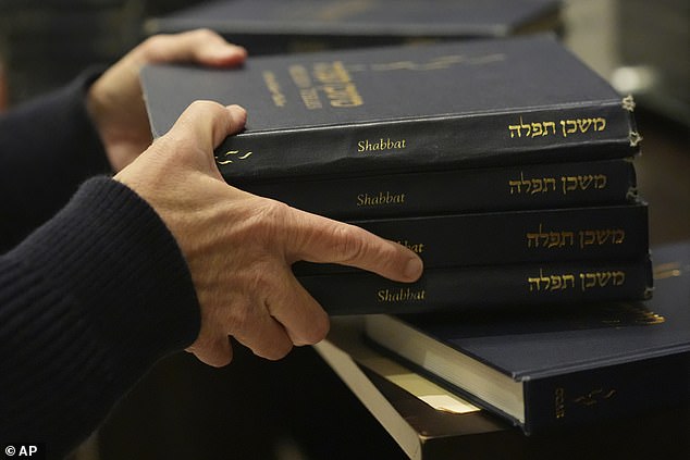 A man hands out prayer books during a Shabbat service on September 27