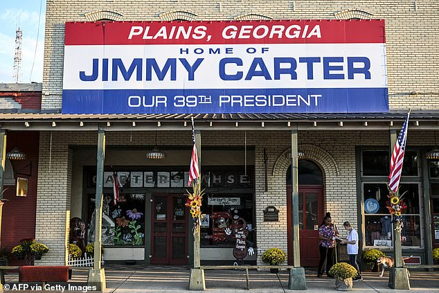 A local Plains resident and friend of former U.S. President Jimmy Carter Gloria English (R), along with her caregiver Stacy Ludden, walk under a sign reading 