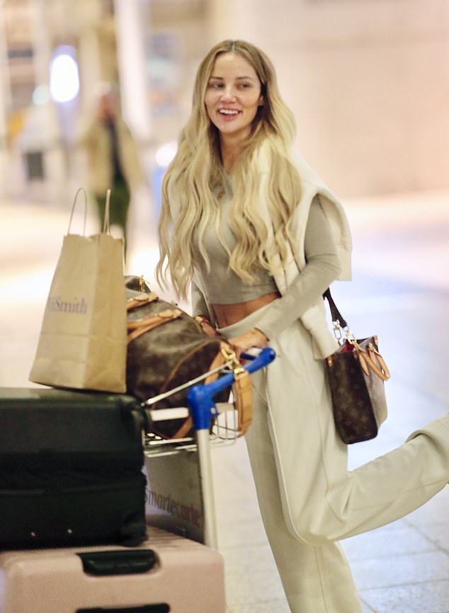 She seemed cheerful despite her recent loss, kicking her heel playfully and smiling as she wheeled her luggage around.